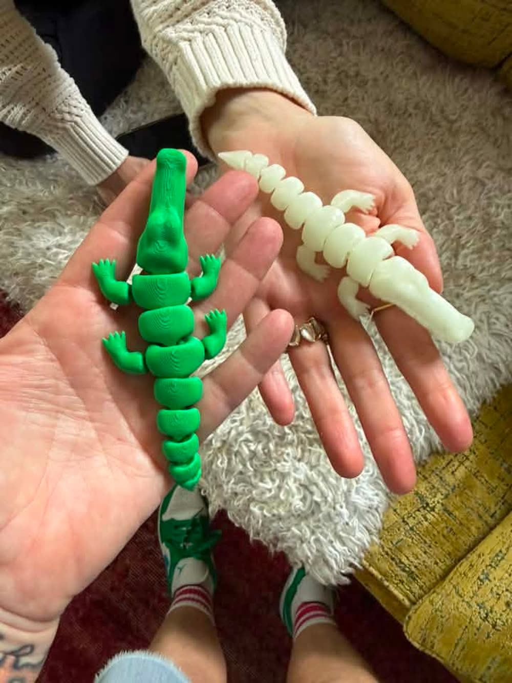A green alligator and a white skeleton toy held in two hands